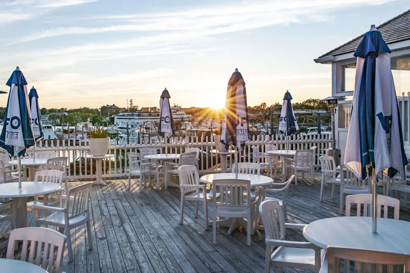 Sunset over the Tugboats deck, umbrellas and tables above Hyannis Harbor