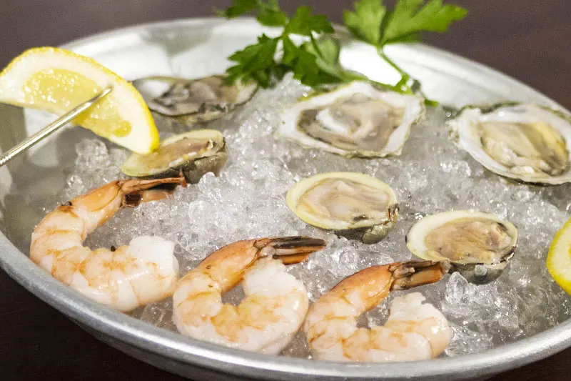Raw bar platter of oysters and shrimp on ice